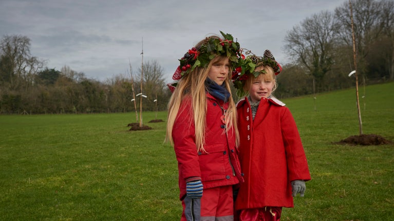 Children wear leaf crowns during a wassail in the orchard at Glastonbury Tor, Somerset